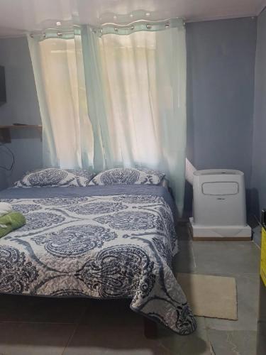 a bedroom with a bed with a blanket and a window at Torito's room in Carrillo