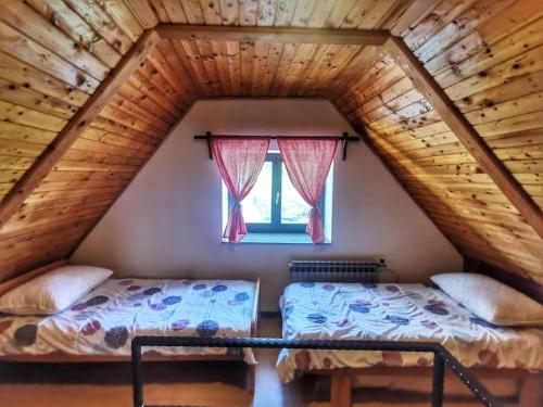 a attic bedroom with two beds and a window at Holiday House - Hidden in Velebit in Senj