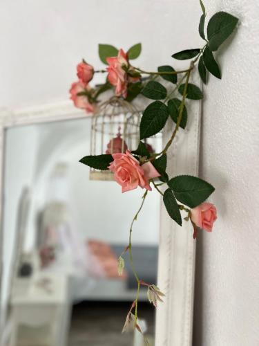 a vase with pink roses in it next to a mirror at Korona Apartman Székesfehérvár in Székesfehérvár
