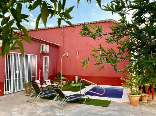 un edificio rosso con due sedie e una piscina di Casa Muriana ad Alanís