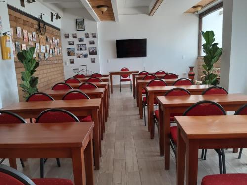 a classroom with wooden tables and red chairs at Hotel El Giro in Villa de Leyva