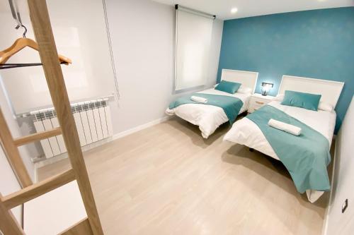 zwei Betten in einem Zimmer mit blauen Wänden in der Unterkunft Pregonero Urban Suites - Azul in Soria