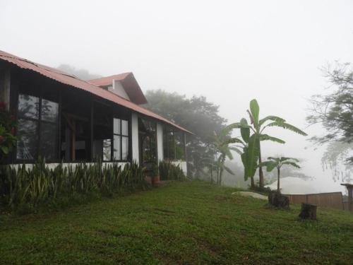 a house in the fog next to a grass yard at hotel y restaurante mirador aires de la sierra, minca in Minca