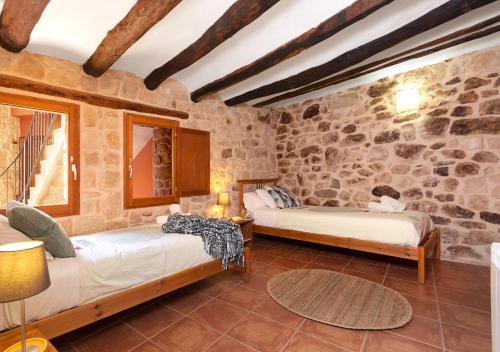 2 letti in una camera con parete in pietra di Patio con barbacoa - Casa de las Letras a Lledó