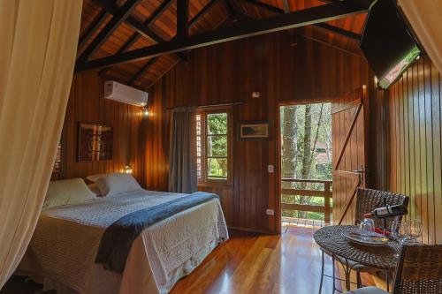 a bedroom with a bed and a table in a room at Pousada Cantos e Contos in Monte Verde