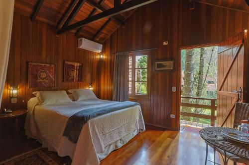 a bedroom with a bed in a room with wooden walls at Pousada Cantos e Contos in Monte Verde