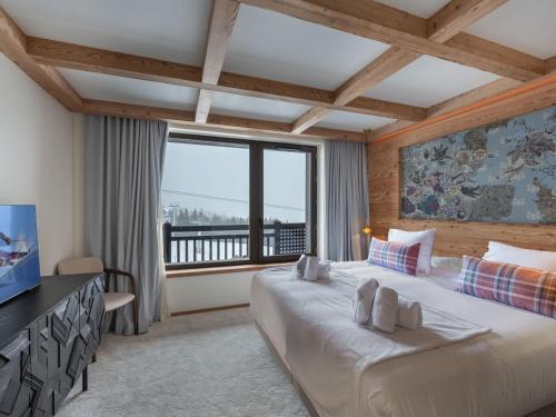 une chambre avec un grand lit et une grande fenêtre dans l'établissement Appartement Neuf à Courchevel 1850 - Ski-in/Ski-out avec Piscine et SPA - FR-1-564-104, à Courchevel