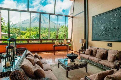 a living room with couches and a large window at Hotel Arenal Kioro Suites & Spa in Fortuna