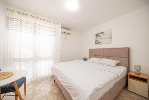 a white bedroom with a bed and a table at Villa Dana in Bar