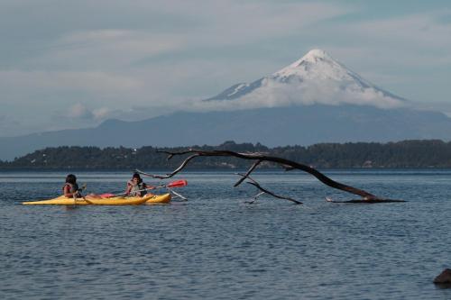 two people in kayaks on a lake with a mountain at Hotel Borde Lago in Puerto Varas