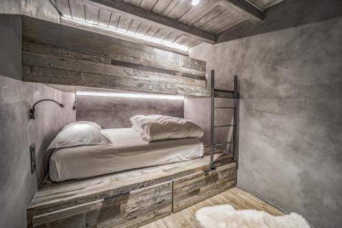 a bed in a room with a wooden wall at Pleta del Tarter Lodge in El Tarter