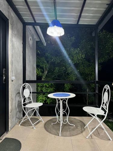 a patio with a table and two chairs and a light at Guest house Me and grandfather-მე და პაპა in Dedoplis Tskaro