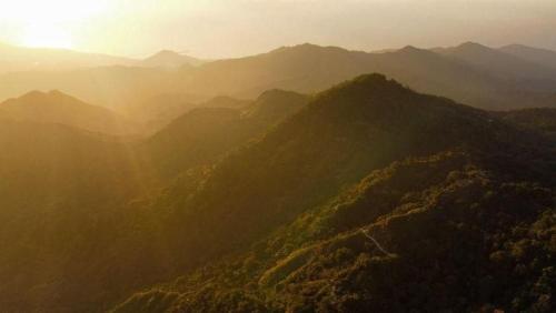 an aerial view of a mountain range with the sun setting at hotel y restaurante mirador aires de la sierra, minca in Minca