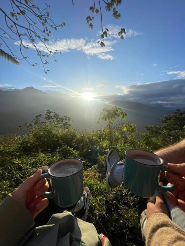 two people holding coffee cups on top of a mountain at hotel y restaurante mirador aires de la sierra, minca in Minca