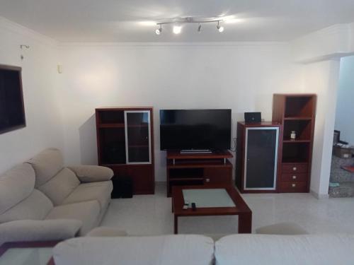 a living room with a couch and a flat screen tv at House Moledo sea view in Moledo