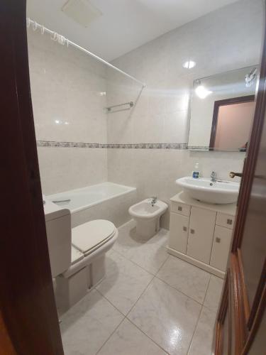 a white bathroom with a toilet and a sink at House Moledo sea view in Moledo