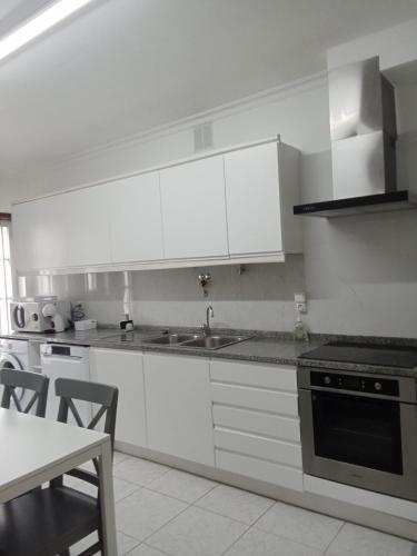 a kitchen with white cabinets and a sink and a table at House Moledo sea view in Moledo