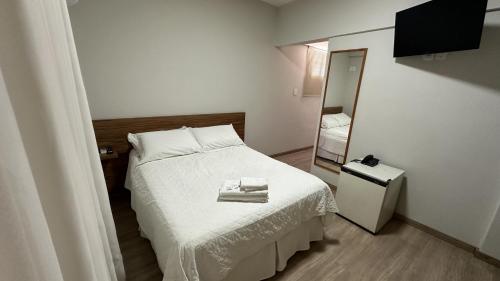 a small bedroom with a bed and a mirror at Xikus Palace Hotel in Guanhães