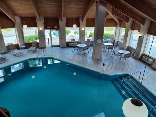 a pool in a hotel with tables and chairs at Baymont by Wyndham Freeport in Freeport