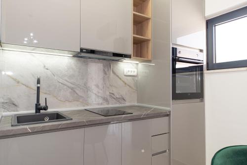 a white kitchen with a sink and a microwave at Villa Dana in Bar