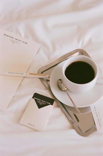 a cup of coffee sitting on a bed with a card at Montauk Yacht Club in Montauk