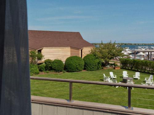 a balcony with white chairs and a yard with a house at Montauk Yacht Club in Montauk