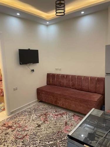a brown couch in a room with a flat screen tv at Aqaba Air Inn in Aqaba