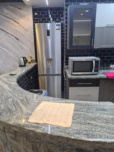 a kitchen with a counter with a microwave and a refrigerator at Aqaba Air Inn in Aqaba