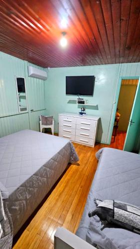 a bedroom with two beds and a flat screen tv at Casa de Temporada Doce Luar in Urubici