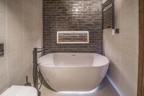 a white tub in a bathroom with a brick wall at Pleta del Tarter Lodge in El Tarter