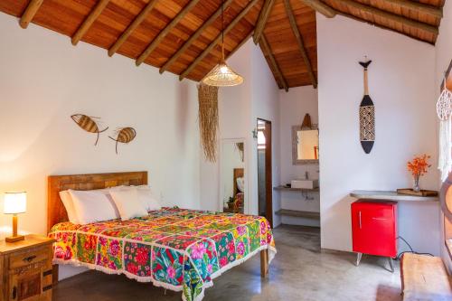 a bedroom with a bed with a colorful bedspread at Chalés Casulo Caraíva in Caraíva