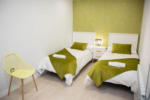 a bedroom with two beds and a yellow chair at Pregonero Urban Suites - Verde in Soria