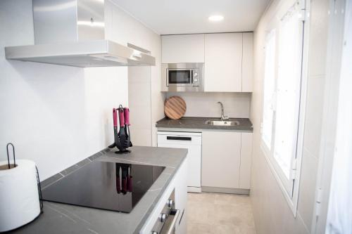 a white kitchen with a sink and a microwave at Pregonero Urban Suites - Verde in Soria