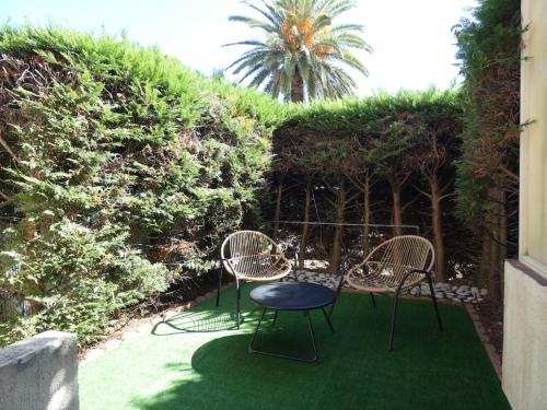 d'une terrasse avec 3 chaises et une table sur gazon. dans l'établissement Studio moderne en rez de jardin, à Antibes