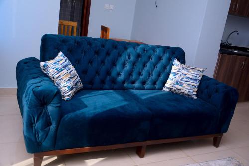 a blue velvet couch with two pillows on it at Kampala suites Kisementi in Kampala