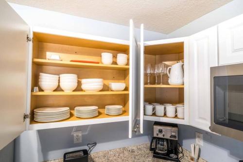 a kitchen cabinet filled with plates and dishes at Charming and delightful getaway! Walk to Beach in Saint Augustine
