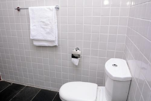 a bathroom with a white toilet and towels at Kampala suites Kisementi in Kampala