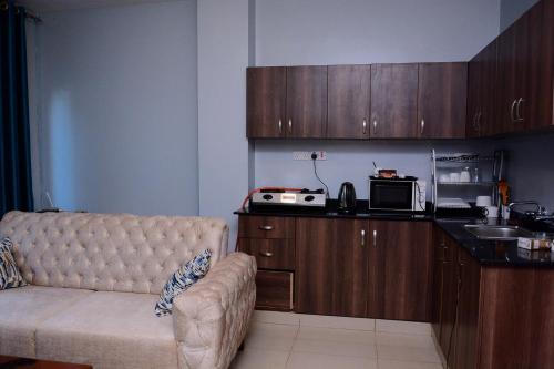 a living room with a couch and a kitchen at Kampala suites Kisementi in Kampala