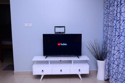 a flat screen tv sitting on top of a white dresser at Kampala suites Kisementi in Kampala