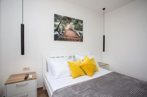 a bedroom with a bed with yellow pillows at Apartments NIKOS FAMILY in Ulcinj