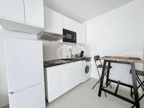 - une cuisine blanche avec une table et un four micro-ondes dans l'établissement Grand studio 5 min des plages, à Antibes