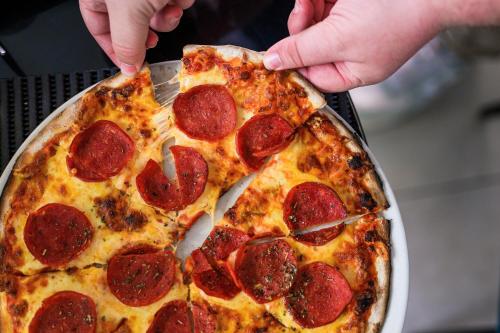 a person holding a slice of pepperoni pizza at La Bella Vita Bellamare in Summerstrand