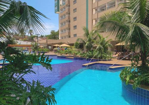 une grande piscine avec des palmiers en face d'un bâtiment dans l'établissement Olimpia Enjoy resort, à Olímpia
