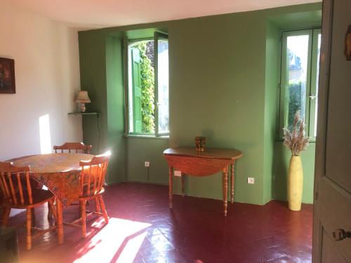 une salle à manger avec des murs verts, une table et des chaises dans l'établissement L'évidence, à Saint-André-de-Valborgne