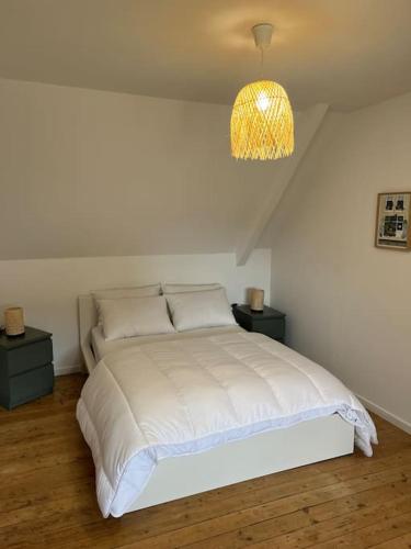 - une chambre avec un lit blanc et un lustre dans l'établissement Ker Bihanic classée 3 étoiles, à Lézardrieux