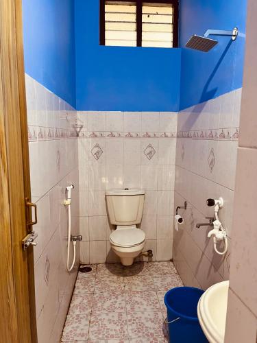 a bathroom with a toilet and a blue wall at Santa Maria Hostel Kovalam in Kovalam