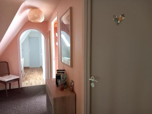 a hallway with pink walls and a table and a mirror at La Chambre d'Agapè in Fouesnant