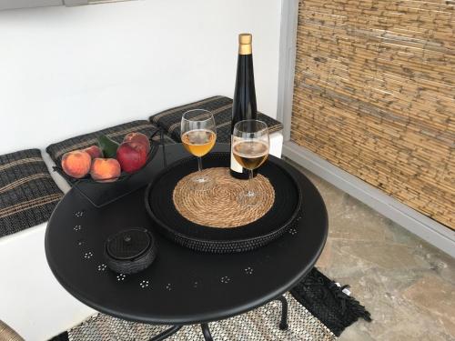 a table with two glasses of wine and a basket of fruit at Darsi suites Kythnos in Kithnos
