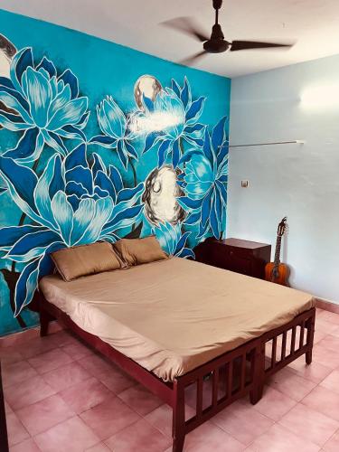 a bed in a room with a painting on the wall at Santa Maria Hostel Kovalam in Kovalam