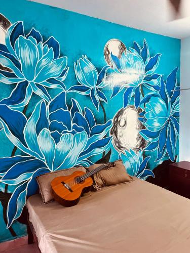 a bedroom with a mural of flowers and a guitar on a bed at Santa Maria Hostel Kovalam in Kovalam